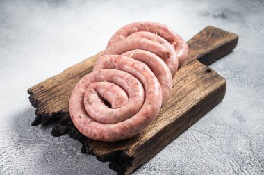 Tahta bir tahtanın üzerinde çiğ domuz eti sosisi pişirmeye hazır. Beyaz arka plan. Üst görünüm.
