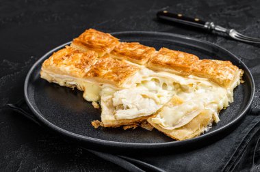 Turkish Su Boregi pie, Tabla borek or burek in plate. Black background. Top view.