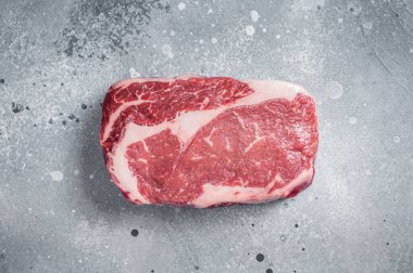 Çiğ kaburga bifteği, kasap tahtasının üzerinde mermer et. Gri arka plan. Üst görünüm.