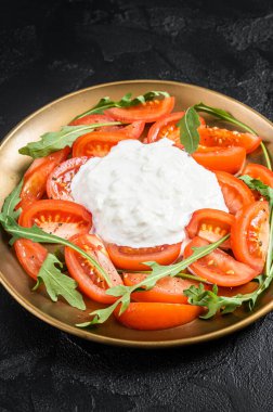 İtalyan salata caprese peynirli stracciatella, domates ve roka. Siyah arka plan. Üst görünüm.