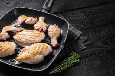 Izgara tavada kızartılmış tavuk eti ve tavuk parçaları - but, göğüs filetosu, kanat, but. Siyah ahşap arka plan. Üst Manzara. Boşluğu kopyala.