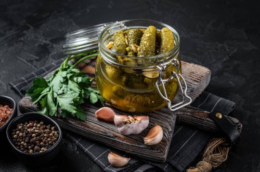 Dereotu, sarımsak ve cam kavanozda baharatlı salatalık turşusu. Siyah arka plan. Üst görünüm.