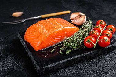 Protein vejetaryen diyeti. Çiğ somon bifteği, otlar ve domates. Siyah arka plan. Üst görünüm.