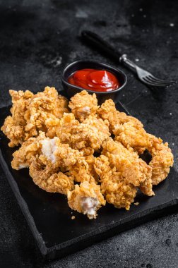 Kızarmış kızarmış ekmek kırıntısı, tavukla kaplı ketçaplı patlamış mısır. Siyah arka plan. Üst görünüm.