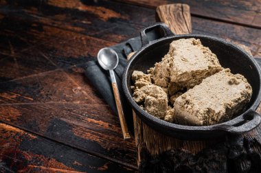 Halva with sunflower seeds and honey in pan. Wooden background. Top view. Copy space.