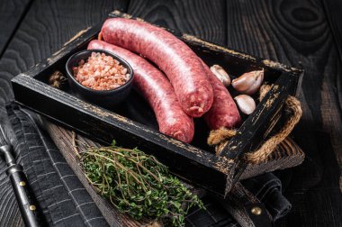 Çiğ sosis Bratwurst, ahşap tepside kekik ile taze et. Ahşap arka plan. Üst görünüm.