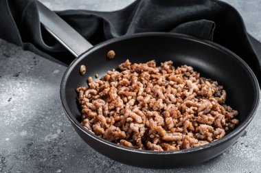 Pan fried minced meat to Italian pasta. Gray background. Top view.