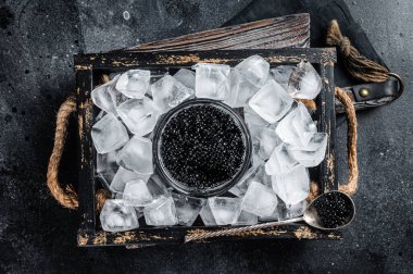 Cam kasede buzla servis edilen siyah havyar, siyah havyarlı kaşık. Siyah arka plan. Üst görünüm.