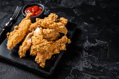 Breaded chicken strips Fingers with Ketchup. Black background. Top view. Copy space.