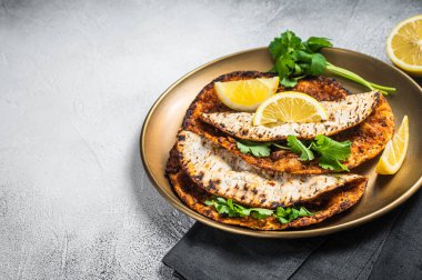 Turkish lahmacun pizza with mince meat and tomatoes on a plate with parsley and lemon. White background. Top view. Copy space.