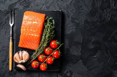 Protein vejetaryen diyeti. Çiğ somon bifteği, otlar ve domates. Siyah arka plan. Üst Manzara. Boşluğu kopyala.