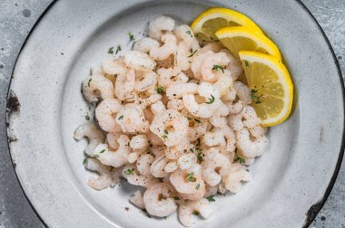 Boiled shrimps seafood with lemon, herbs and spice, prawns peeled. Gray background. top view.