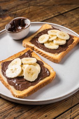 Çikolatalı, fındık ezmeli ve muzlu sandviç pişirmek. Ahşap arka plan. Üst görünüm.