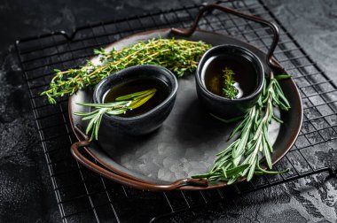 Assorted fresh herbs with olive oil. Top view. Dark background.