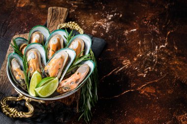Steamed cooked Green mussels with herbs and spices in a skillet. Dark background. Top view. Copy space.