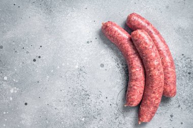 Raw beef meat sausages ready for cooking. Gray background. Top view. Copy space.