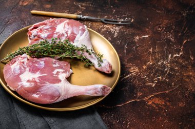 Raw duck legs. Poultry meat ready to cook. Dark background. Top view. Copy space.