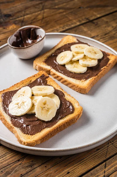 Çikolatalı, fındık ezmeli ve muzlu sandviç pişirmek. Ahşap arka plan. Üst görünüm.