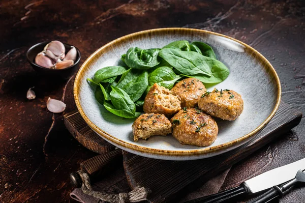 Fish Cakes or Fish balls with tuna and spinach in a plate. Dark background. Top view.