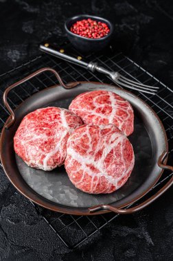 Raw pork cutlet, Crepinette with spices and herbs. Black background. Top view.