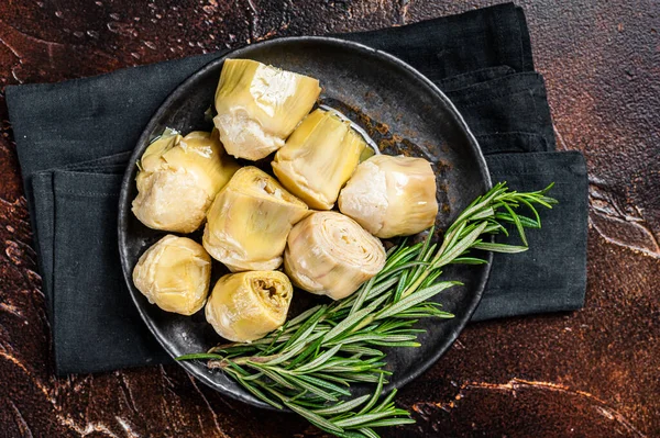 Italian appetizer Artichoke hearts pickled in olive oil with herbs and spices Dark background. Top view.