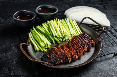 Peking Duck served with cucumber, green onions, and roasted wheaten chinese pancakes with sauce Hoysin. Black background. Top view.