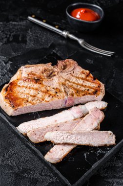 Grilled slised pork Chop or T-bone meat steak. Black background. Top view.