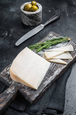 Tahta kesme tahtasına dilimlenmiş Hollanda keçi peyniri. Siyah arka plan. Üst görünüm.