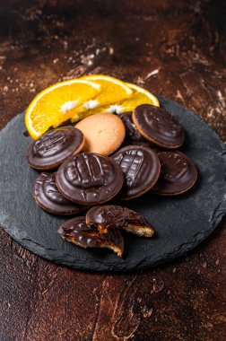 Stack of Chocolate Covered Round Jaffa Cookies with Orange Flavored Marmalade. Dark background. Top view.
