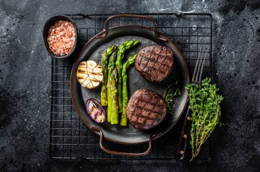 Grilled Fillet Mignon Steak with roasted asparagus. Black background. Top view.