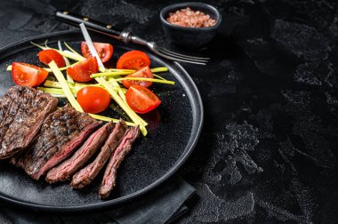 Grilled arrachera Skirt steak with garnish. Black background. Top view. Copy space.