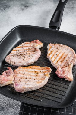 Fried on a grill skillet pork chop steaks. White background. Top view.