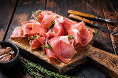 Jamon serrano jambonu dilimleri ya da ahşap tahtada biberiyeli prosciutto crudo parma. Ahşap arka plan. Üst görünüm.