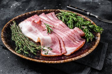 Çiğ domuz pastırması otlarla pişirilmeye hazır. Siyah arka plan. Üst görünüm.