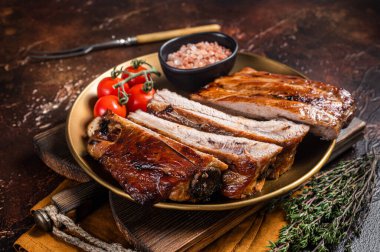 Barbekü soslu domuz pirzolası ve şifalı otlar. Karanlık arka plan. Üst görünüm.