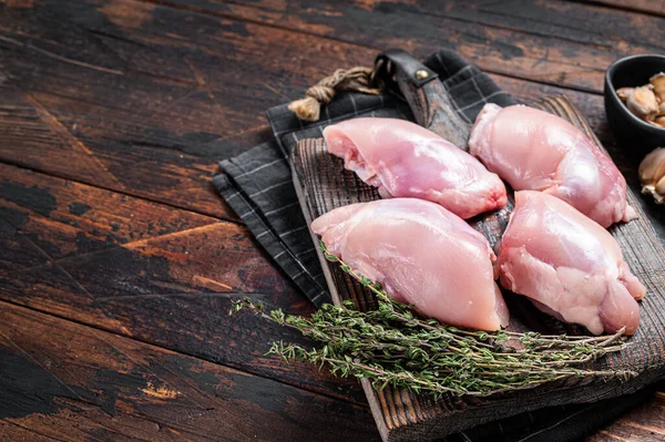 Chicken thigh fillet, Raw Boneless and skinless meat on a cutting board. Wooden background. Top view. Copy space.