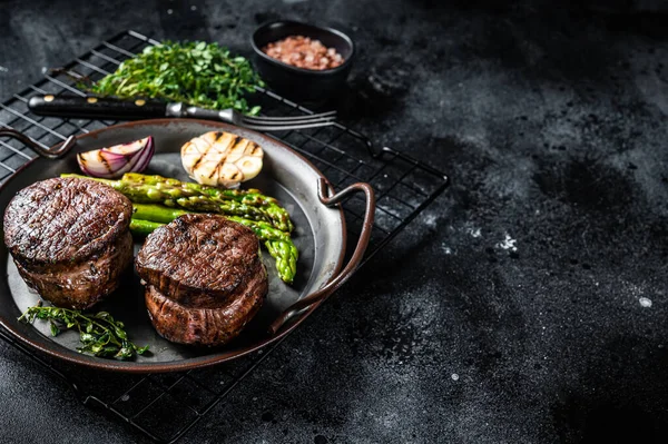 Grilled Fillet Mignon Steak with roasted asparagus. Black background. Top view. Copy space.