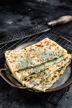 Gozleme Turkish flatbread with greens and cheese. Black background. Top view.