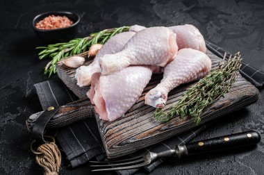 Taze çiğ tavuk budu bacakları tahta kesme tahtasının üzerinde. Siyah arka plan. Üst görünüm.