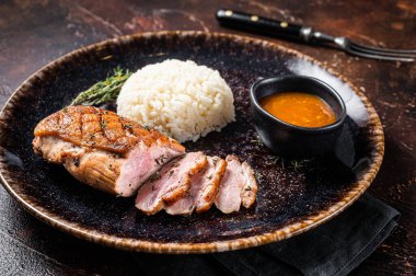 Kızarmış ördek göğsü bifteği, soslu tavuk fileto ve pilav. Karanlık arka plan. Üst görünüm.