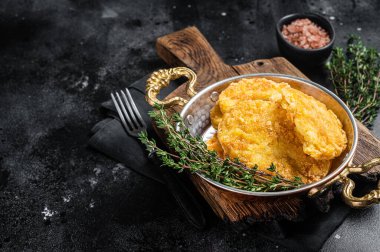 Fried Hash brown potato, hashbrown in a skillet. Black background. Top view. Copy space.