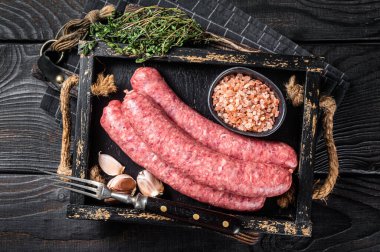 Çiğ sosis Bratwurst, ahşap tepside kekik ile taze et. Ahşap arka plan. Üst görünüm.