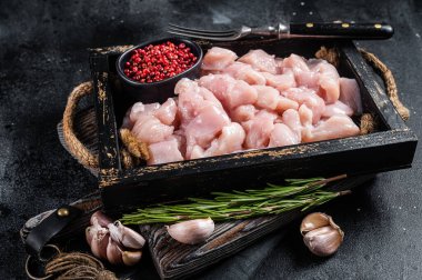 Çiğ doğranmış tavuk göğsü filetoları, tahta tepside doğranmış kümes hayvanları eti. Siyah arka plan. Üst görünüm.