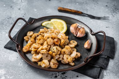 Grilled Shrimps prawns with garlic, olive oil and lemon in a tray. Gray background. top view.