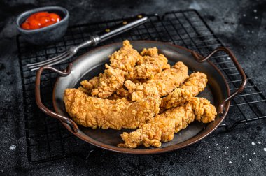 Crispy chicken tenders strips with Ketchup. Black background. Top view.