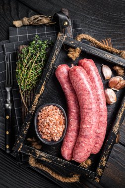 Çiğ sosis Bratwurst, ahşap tepside kekik ile taze et. Ahşap arka plan. Üst görünüm.