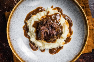 Kırmızı şarap soslu ve patates püresiyle yavaş pişmiş sığır eti yanakları. Karanlık arka plan. Üst görünüm.