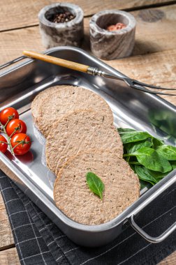 Bitki temelli etten yapılmış çiğ et köfteleri mutfak tepsisinde otlu taze vegan burger pirzolası. Ahşap arka plan. Üst görünüm.