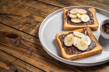 Cooking of sandwich with chocolate Hazelnut butter and bananas. Wooden background. Top view. Copy space.