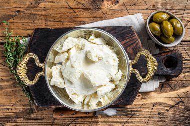 Zeytin ve biberiyeli bir tavada keçi ve koyun peyniri. Ahşap arka plan. Üst görünüm.